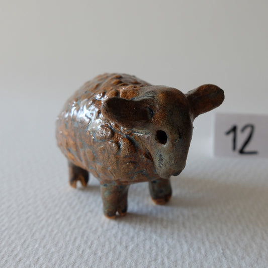 Handcrafted ceramic sheep figurine "The Woolly Sheep (#12)" in stoneware by Nikolaj Jesper Cyon. Standing on four legs, featuring a textured woolly fleece glazed in warm brown tones with a expressive sculpted face and drooping ears.